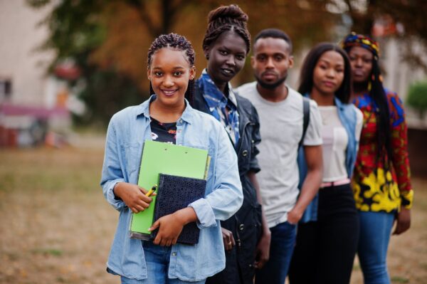 Row of group five african college students spending time together on campus at university yard. Black afro friends studying. Education theme.